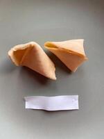 Broken fortune cookie with a blank paper slip on a gray background. Moment of anticipation and mystery that accompanies the opening of a fortune cookie photo