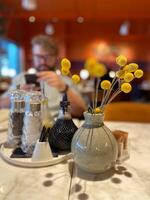 Table with decorative vase and condiment set in cozy restaurant ambiance. Warmth and elegance of a dining table setting, highlighting the intricate details of the decorations photo