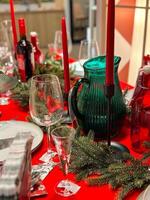 Christmas set table is adorned with festive decorations, ready for a joyful winter holiday gathering. Vibrant red tablecloth and elegant tableware create a warm and inviting atmosphere photo