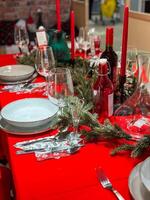 Christmas set table is adorned with festive decorations, ready for a joyful winter holiday gathering. Vibrant red tablecloth and elegant tableware create a warm and inviting atmosphere photo