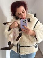 Cozy moment captured as woman holds a Siamese cat and takes a mirror selfie. Dressed in a fluffy jacket and holding smartphone, warm and intimate scene is framed by the hallway background photo