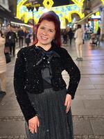 Millennial woman standing outdoors at Christmas night,. City lights in the background create a warm and Christmas holidays atmosphere, enhancing the peaceful and confident expression on her face photo