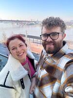 Man and woman taking selfie in cold time outdoor. Couple enjoying a beautiful day by the river with a breathtaking view. Moment of connection and joy together photo