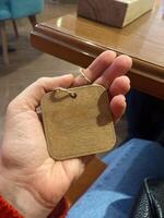Close-up hand holds a small wooden tag with a twine loop. Copy space and empty place for text. Natural texture and simplicity of the tag create a connection to artisanal craftsmanship photo