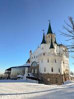 Beautiful white princess castle building stands majestically on a snowy landscape under a clear blue sky. Architectural design and winter setting create a fairy tail and fantasy photo