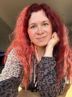 Portrait smiling woman with vibrant red hair basks in the glow of sunlight. her relaxed expression and comfortable attire create an atmosphere of warmth and contentment. photo