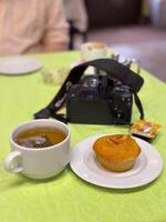 Cozy cafe setting with a cup of tea, a muffin, and a camera on a green table. Harmony of relaxation, creativity and indulgence photo