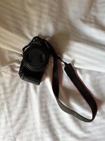 Camera with a strap placed on a white bed sheet, capturing the essence of travel preparation and creativity. Simplicity, creative and readiness of a photographer journey. Top view photo