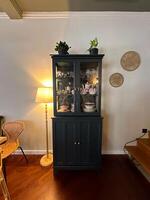 Classic wooden cabinet stands elegantly in a cozy room, displaying exquisite china and adorned with potted plants. warm lighting photo