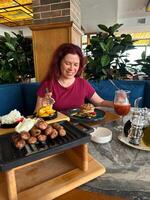 Millennial woman enjoys a beautifully prepared meal in a cozy restaurant setting, engaging in a delightful dining experience surrounded by greenery. Inviting atmosphere emphasizes comfort photo