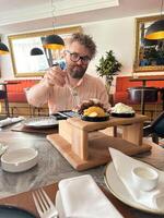 Millennial man enjoys a delicious dish in a stylish restaurant, emphasizing comfort and culinary delight. Elegant atmosphere combines modern decor with gastronomic pleasure. Meat food photo