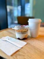 Morning breakfast of yogurt parfait with granola and a hot coffee to go in a cozy cafe setting. Relaxing and inviting atmosphere perfect for breakfast photo