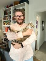 Warm moment between a millennial man and his cat, bond and affection shared in a cozy home environment. The background features a bookshelf at home. Pet and friendship concept photo