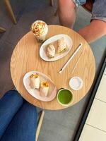 Healthy snack and drink on a wooden cafe table. Enjoy a delicious and nutritious break with wraps and vibrant beverages. photo