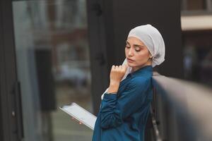 Smiling muslim girl using digital tablet, browsing Internet or social networks outdoor and copy space photo