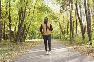 Cheerful young man in stylish clothes walks in autumn park on sunny warm autumn day. Concept of weekend and outdoor recreation photo