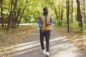 Hipster african american man walking in autumn park photo