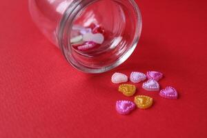 Rhine pink yellow hearted cards poured out of a glass can of flasks on a red background with a copyspace valentine's day photo