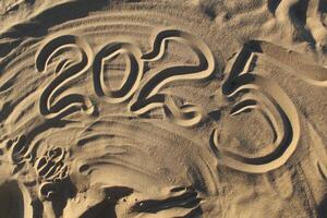 The inscription is the number 2025 on the sand on the beach of the sea of the river. New Year Christmas in warm countries photo