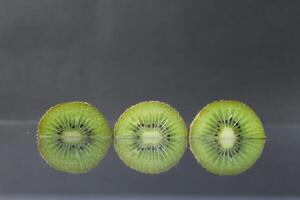 two or three circles of green kiwi semicircle with a black glossy still life photo