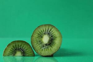 half and a circle of kiwi kusrchek with reflection on a green background with a copyspace photo