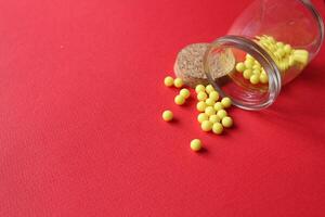 Homeopathy vitamins are scattered on a red background with a copyspace place for text. photo