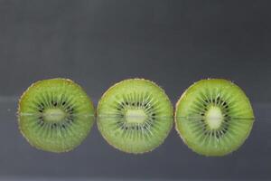 two or three circles of green kiwi semicircle with a black glossy still life photo