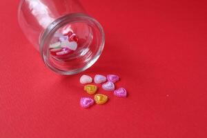 Rhine pink yellow hearted cards poured out of a glass can of flasks on a red background with a copyspace valentine's day photo