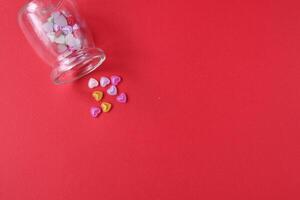 Rhine pink yellow hearted cards poured out of a glass can of flasks on a red background with a copyspace valentine's day photo