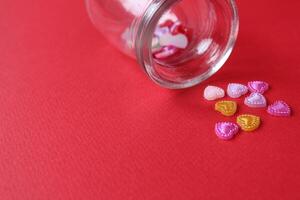 Rhine pink yellow hearted cards poured out of a glass can of flasks on a red background with a copyspace valentine's day photo