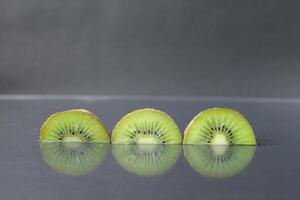 two or three circles of green kiwi semicircle with a black glossy still life photo