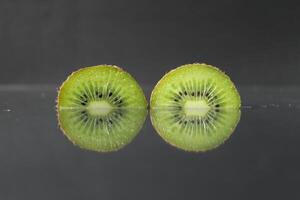 two or three circles of green kiwi semicircle with a black glossy still life photo