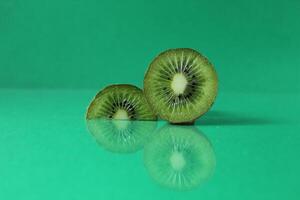 half and a circle of kiwi kusrchek with reflection on a green background with a copyspace photo