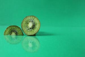 half and a circle of kiwi kusrchek with reflection on a green background with a copyspace photo