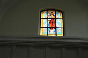 Stained glass on the window on a gray background with space for copyspace text. Stained-glass window in the church, temple, catholic photo
