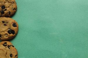 Chocolate chip cookie background on a green background with space for copyspace text. Food background photo
