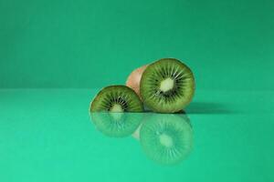 half and a circle of kiwi kusrchek with reflection on a green background with a copyspace photo