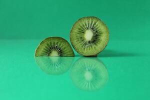 half and a circle of kiwi kusrchek with reflection on a green background with a copyspace photo