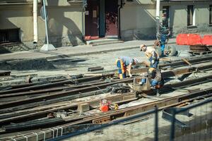 Group of workers welding rails, repairing tram tracks. Urban renovation, transport infrastructure photo