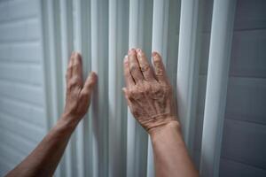 Closeup of hands mature woman warming hands on heater at home during cold weather in heating season. photo