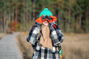 Curious woman with binoculars observe wildlife, landscape in autumn nature park. Environment save photo