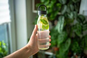 Water with mint, thyme, lime for drinking outside in hot weather, bottle with mint and lemon water photo