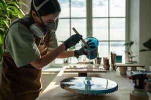 Concentrated woman, liquid artist creating pattern on canvas while working with epoxy resin painting photo