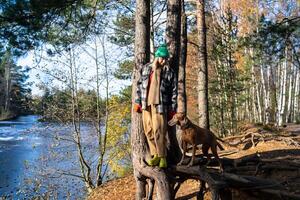 Contented dog owner woman enjoys walk with pet vizsla in forest near frozen river in late fall day. photo