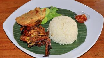 Grilled chicken rice and fried tempeh served on a plate photo