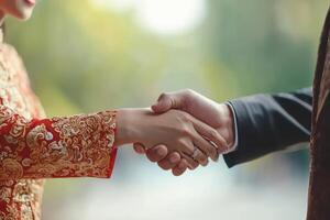 Asian businessman and businesswoman shaking hands in traditional attire photo