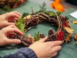 Hands Arranging a Rustic Autumnal Wreath with Pine Cones, Berries, and Twigs photo