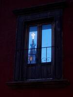 A cross is reflected in a window of a building photo
