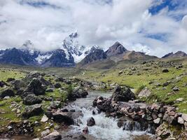 A stream running through a rocky field with mountains in the background photo