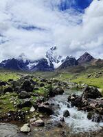 A river flowing through a rocky field with mountains in the background photo